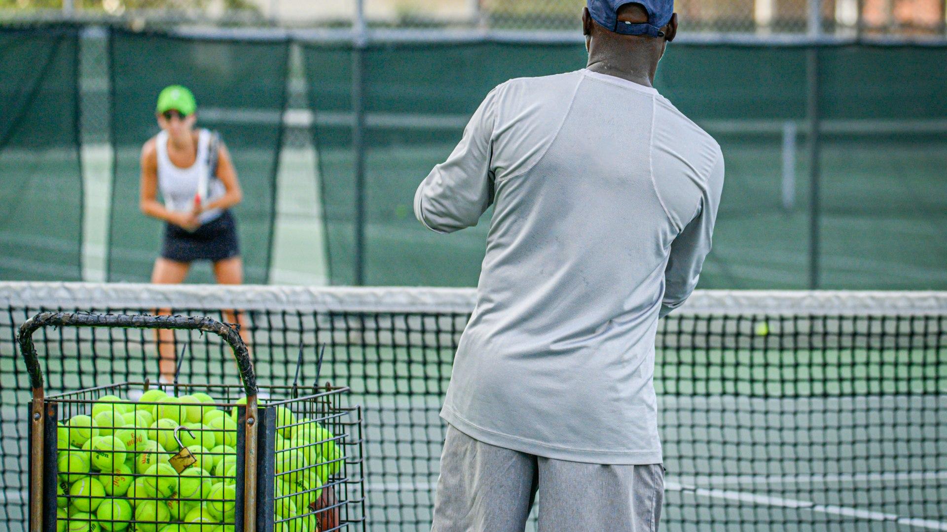 A coach feeding balls during a lesson